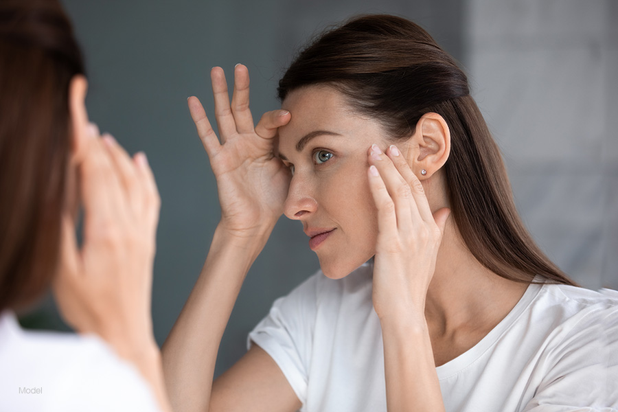 close-up of a woman looking in a mirror and touching her face.